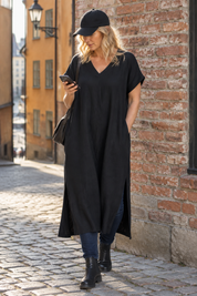 Svart klänning med blå jeans, vid tegelvägg
